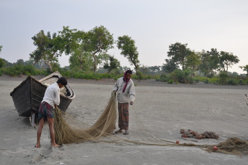 Two fisherman doing the repair work on their fishing net on the Kuakata beach