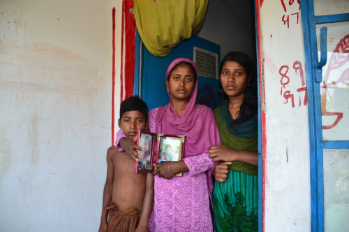 Shirin Begum holds the pictures of Rumi, while her other children look on, outside their newly acquired home.