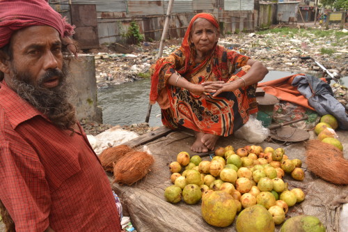 A trader sells her produce right next to the filthy canal, also using polythene bags.