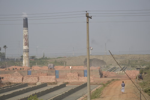 Unbaked bricks waiting to be baked in the large kiln in the Savar area. The smog from the kilns are visible in the air surrounding the kiln.