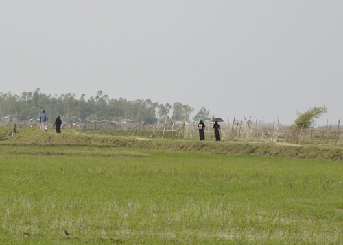 Two young women, clad in burkhas, cross one of the expanses of green in Gandamara 