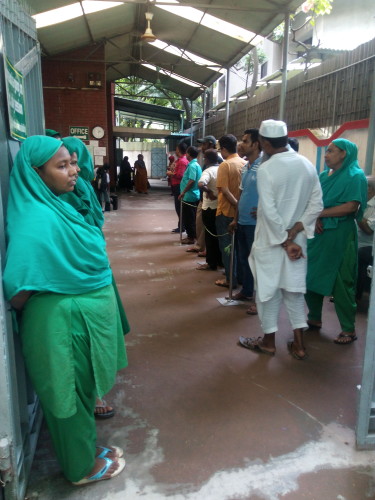 Parents line up inside the entrance to a Dhaka school as a woman in green watches out for any suspicious presence